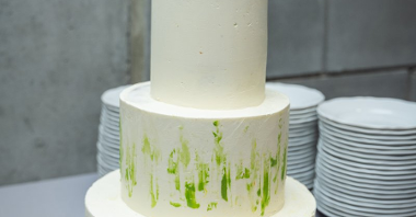 Zdjęcie przedstawia trzypoziomowy, biały tort zwieńczony logotypem firmy Grace.