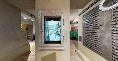 Element wystawy muzealnej, który przedstawia okno Paprzyckiego. W ramie okna kamienicy jest powieszon monitor, który wyświetla zdjęcia Leszka Paprzyckiego.